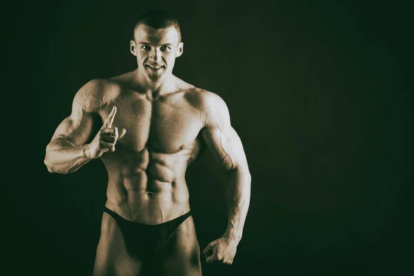 Mooie bodybuilder op een zwarte achtergrond — Stockfoto