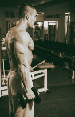 Genç adam spor salonunda antrenman yapıyor.