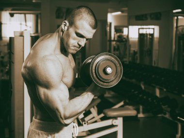 Genç adam spor salonunda antrenman yapıyor.