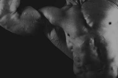 Siyah arka planda poz veren genç kaslı vücut geliştirici.