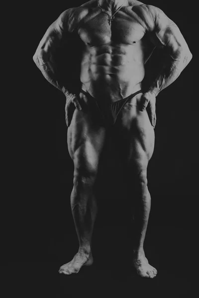 Um homem com um corpo muscular lindo em um fundo preto — Fotografia de Stock