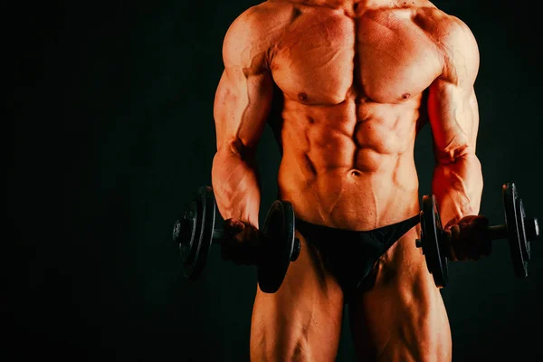 Giovane bodybuilder muscolare posa su sfondo nero — Foto Stock