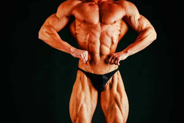 Joven musculoso culturista posando sobre fondo negro — Foto de Stock