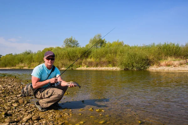 Junger Mann angelt. Angeln am Gebirgsfluss. Forellenfischen. — Stockfoto