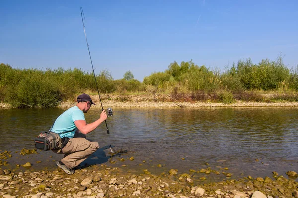 Young man fishing. Fishing on the mountain river. Trout fishing.