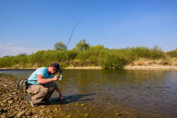 Young man fishing. Fishing on the mountain river. Trout fishing.
