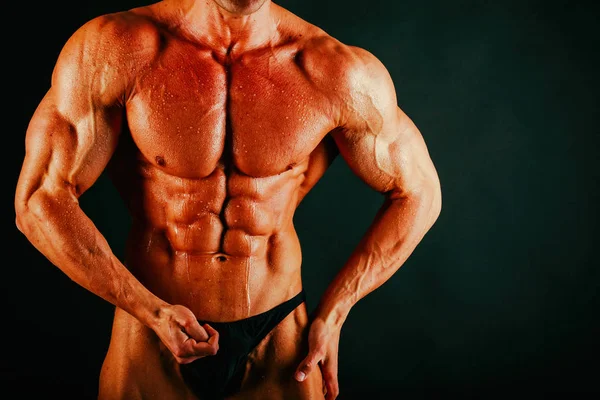 Bodybuilder muscolare sano su uno sfondo nero — Foto Stock