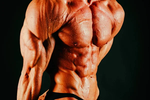 Bodybuilder muscolare sano su uno sfondo nero — Foto Stock