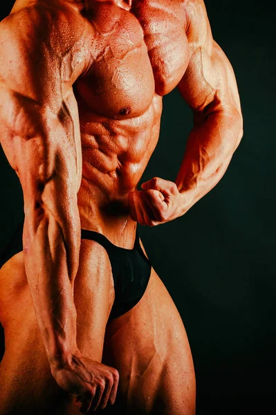 Bodybuilder muscolare sano su uno sfondo nero — Foto Stock