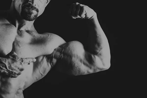 Joven musculoso culturista posando sobre fondo negro — Foto de Stock