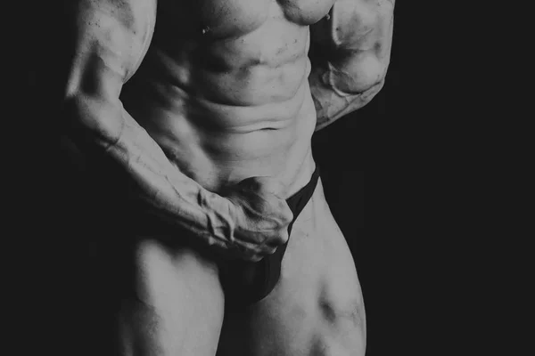 Jovem musculoso fisiculturista posando sobre fundo preto — Fotografia de Stock