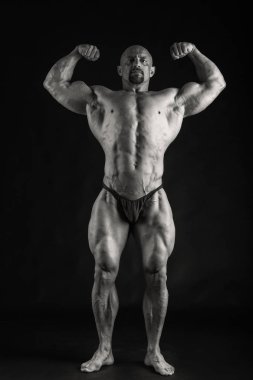 Siyah bir arka plan üzerinde poz acemi vücut geliştirmeci