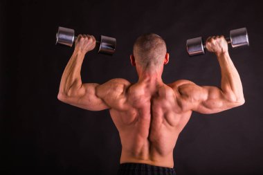 adam siyah bir zemin üzerine dumbbells ile