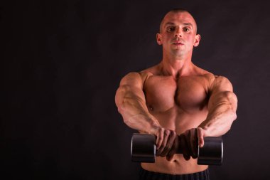 adam siyah bir zemin üzerine dumbbells ile