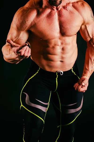 Homem musculoso treinado em um fundo preto — Fotografia de Stock