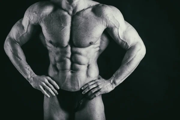 Músculos masculinos em um fundo preto — Fotografia de Stock