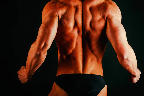 Músculos masculinos em um fundo preto — Fotografia de Stock