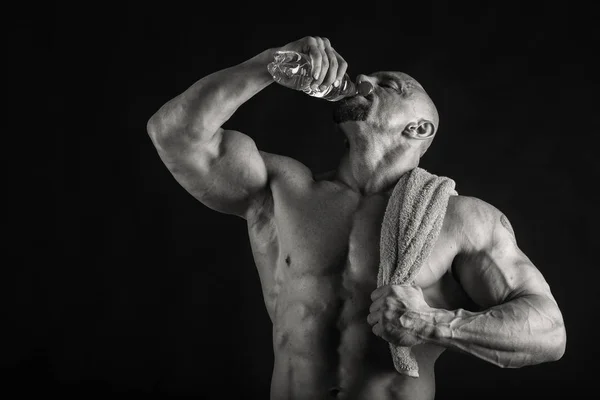 Novice bodybuilder posing on a black background — Stock fotografie