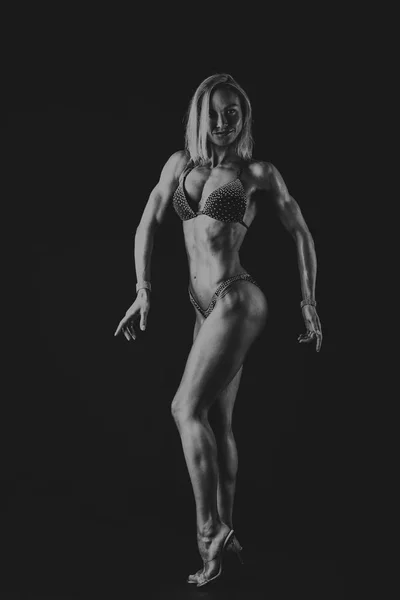 Treinamento elegante, mulher muscular em um fundo preto — Fotografia de Stock