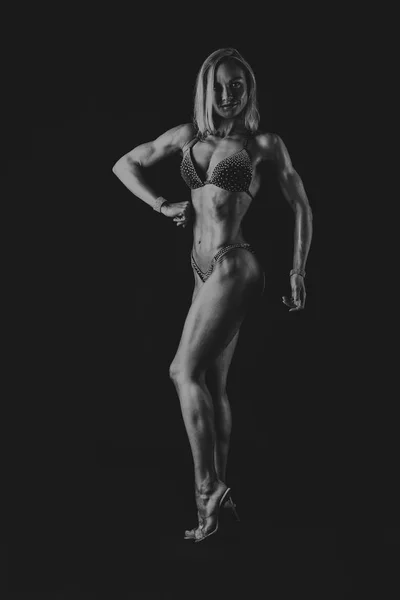 Elegante allenamento, donna muscolosa su sfondo nero — Foto Stock