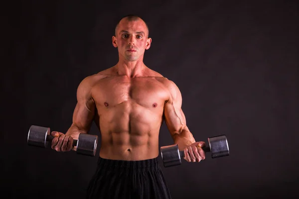 Adam siyah bir zemin üzerine dumbbells ile — Stok fotoğraf