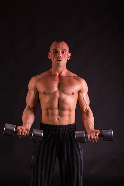 Adam siyah bir zemin üzerine dumbbells ile — Stok fotoğraf