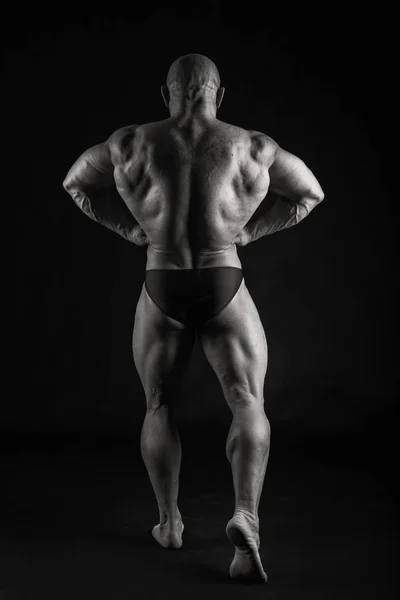 Kraftvoller Bodybuilder auf schwarzem Hintergrund — Stockfoto