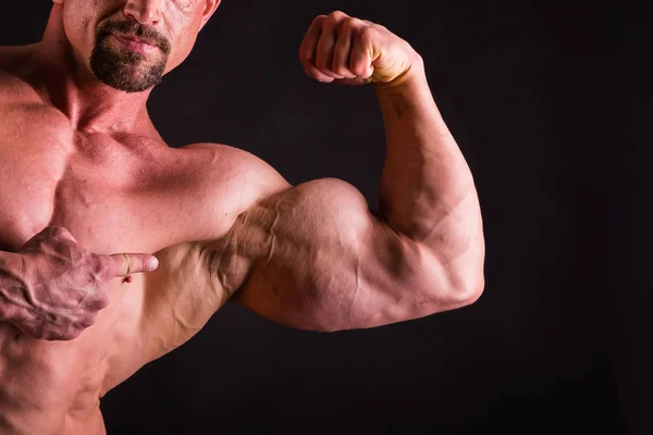 Fisiculturista mostrando suas costas e músculos bíceps, fitnes pessoais — Fotografia de Stock