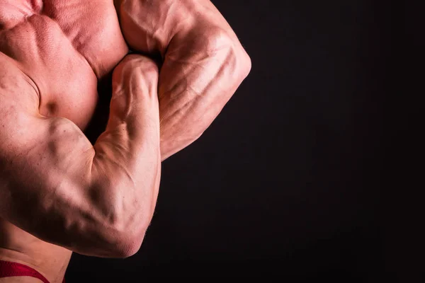 Fisiculturista posando em diferentes poses demonstrando seus músculos. Falha num fundo escuro. Homem mostrando músculos se esforçando. Bonito atleta corpo muscular . — Fotografia de Stock