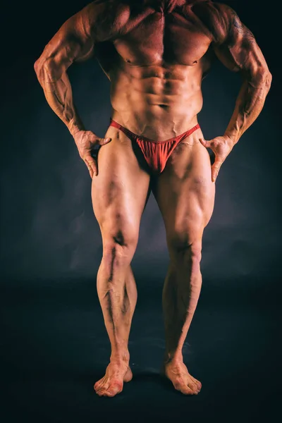 Culturista posa in pose diverse dimostrando i loro muscoli. Fallimento su uno sfondo scuro. Maschio che mostra tensione muscolare. Bellissimo atleta del corpo muscolare . — Foto Stock