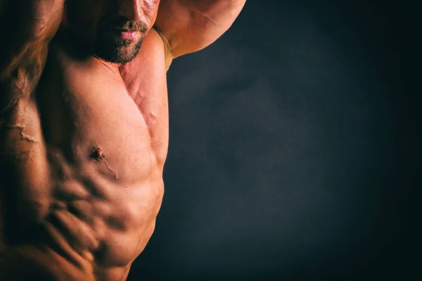 Fisiculturista posando em diferentes poses demonstrando seus músculos. Falha num fundo escuro. Homem mostrando músculos se esforçando. Bonito atleta corpo muscular . — Fotografia de Stock