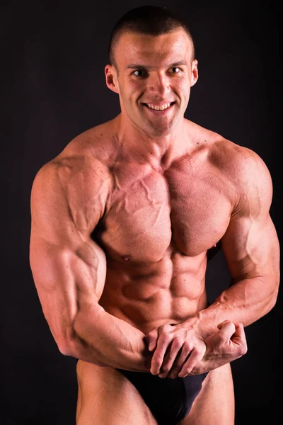 Handsome power athletic man in training pumping up muscles with — Stock Photo, Image