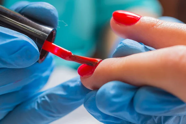 Vrouw in nagel salon manicure door schoonheidsspecialiste ontvangen. Close-up van vrouwelijke hand rustend op witte tovel — Stockfoto