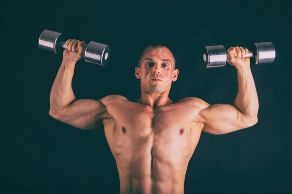 Muscular, relief body bodybuilder on a black background. Black a — Stock Photo, Image