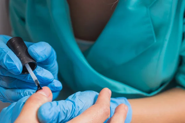 Donna in salone di bellezza che riceve la manicure da estetista. primo piano della mano femminile appoggiata su una paletta bianca — Foto Stock