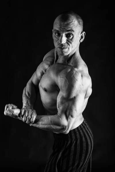 Un hombre con un cuerpo musculoso magnífico sobre un fondo negro — Foto de Stock