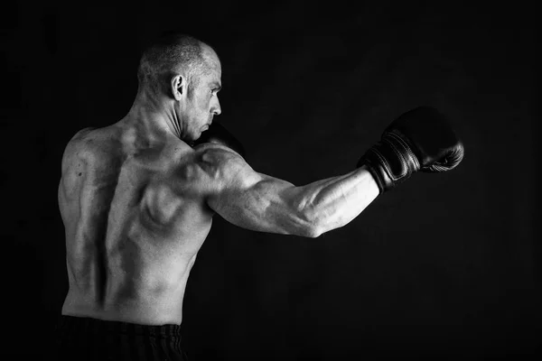 Un hombre con un cuerpo musculoso magnífico sobre un fondo negro — Foto de Stock