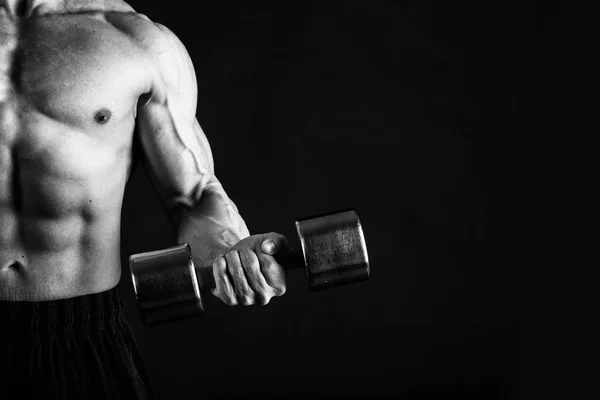 Un hombre con un cuerpo musculoso magnífico sobre un fondo negro —  Fotos de Stock