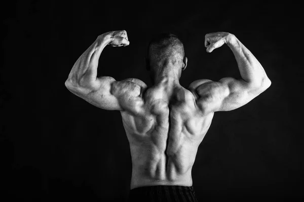 Un homme avec un corps musclé magnifique sur un fond noir — Photo