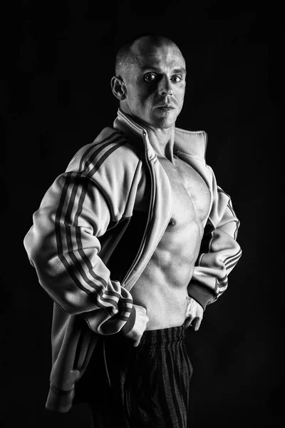 Um homem com um corpo muscular lindo em um fundo preto — Fotografia de Stock