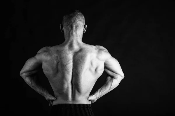 Een man met een schitterende gespierd lichaam op een zwarte achtergrond — Stockfoto