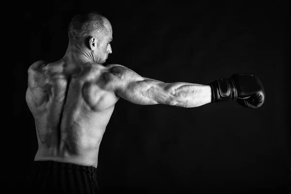 Um homem com um corpo muscular lindo em um fundo preto — Fotografia de Stock