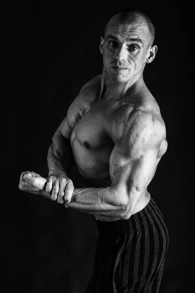 Un hombre con un cuerpo musculoso magnífico sobre un fondo negro — Foto de Stock