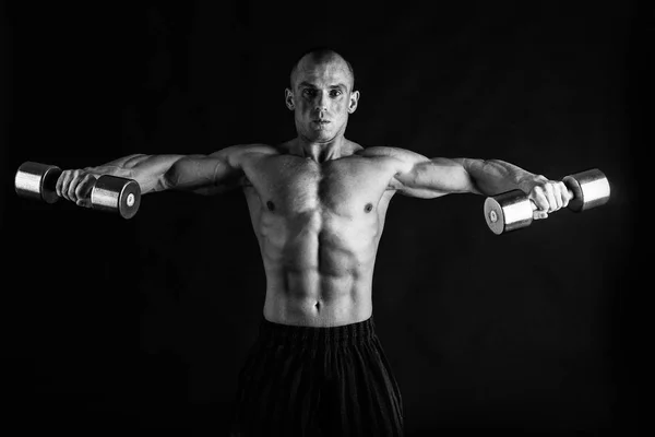 Un hombre con un cuerpo musculoso magnífico sobre un fondo negro — Foto de Stock