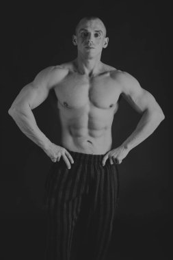 Acemi vücut geliştirmeci bir siyah beyaz fotoğraf üzerinde poz.