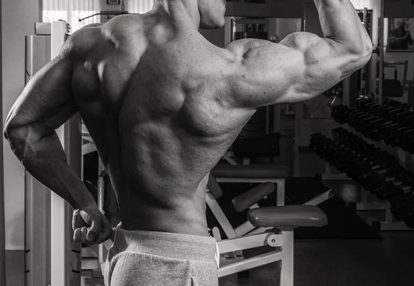 Muskulös bodybuilder killen gör övningar i gymmet — Stockfoto