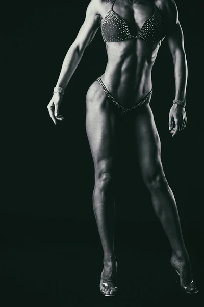 Elegant training, muscular woman on a black background