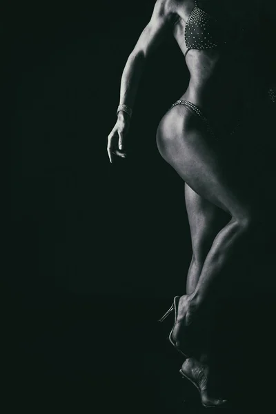 Entrenamiento elegante, mujer musculosa sobre un fondo negro —  Fotos de Stock