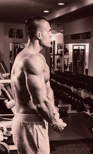 Fisiculturista mostrando suas costas e músculos bíceps, fitnes pessoais — Fotografia de Stock