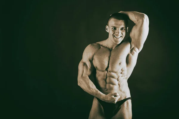 Bodybuilder op een donkere achtergrond. — Stockfoto